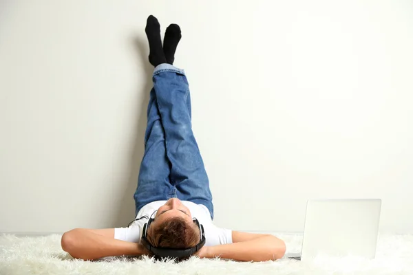 Young man relaxing on carpet and listening to music — Stock Photo, Image