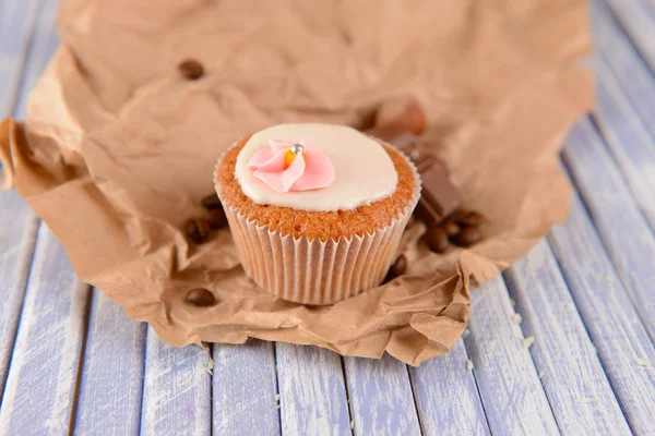 Tasty cupcake with butter cream, on color wooden table, on wooden background — Stock Photo, Image