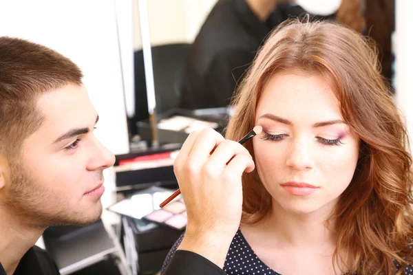 Mladý kluk kadeřník dělá make-up krásná žena v salonu krásy — Stock fotografie