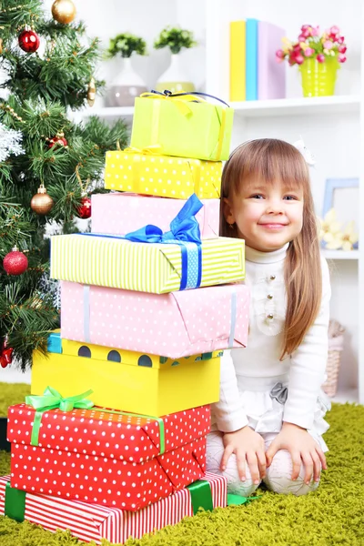 Маленька дівчинка з подарунками біля ялинки в кімнаті — стокове фото