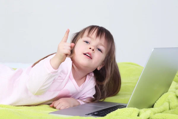 Küçük kız yatakta duvar arka plan üstünde laptop — Stok fotoğraf