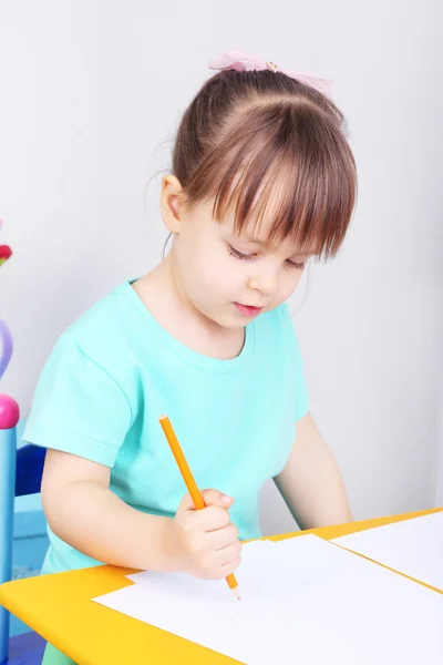 Petite fille dessine assis à table dans la chambre — Photo