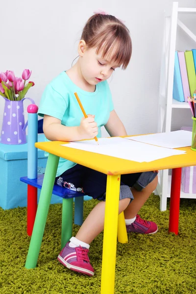 Kleines Mädchen zeichnet am Tisch im Zimmer sitzend — Stockfoto