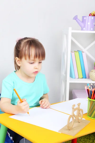 Menina desenha sentado à mesa no quarto — Fotografia de Stock