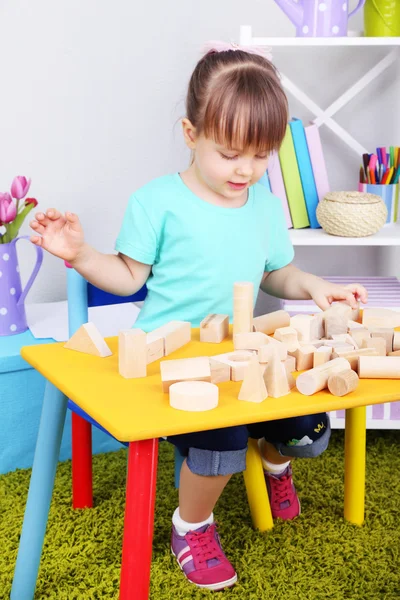 Klein meisje speelt met bouw blokken zitten aan tafel op kamer — Stockfoto