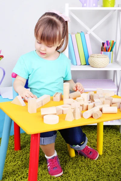 Κοριτσάκι παίζει με την κατασκευή μπλοκ κάθεται σε τραπέζι στην αίθουσα — Φωτογραφία Αρχείου