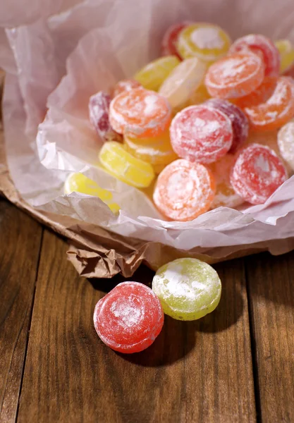 Sweet multicolor candies on paper, on wooden background — Stock Photo, Image