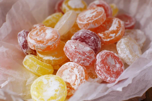 Sweet multicolor candies on paper, on wooden background — Stock Photo, Image