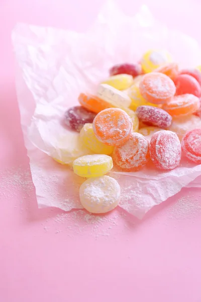 Γλυκό πολύχρωμα ζαχαρωτά σε χαρτί, σε φόντο χρώμα — Φωτογραφία Αρχείου