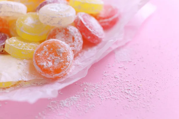 Dulces caramelos multicolores sobre papel, sobre fondo de color — Foto de Stock