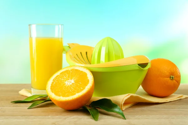 Citrus press and oranges on table on blue background — Stock Photo, Image