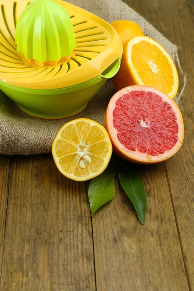 Citrus press and fruits on wooden background — Stock Photo, Image