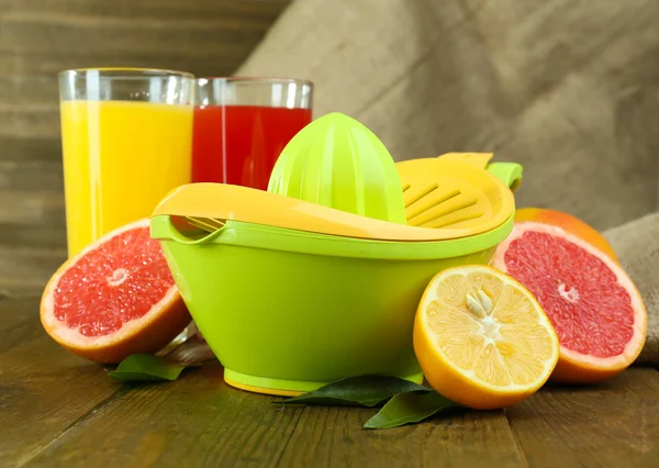 Citrus press and fruits on table on wooden background — Stock Photo, Image