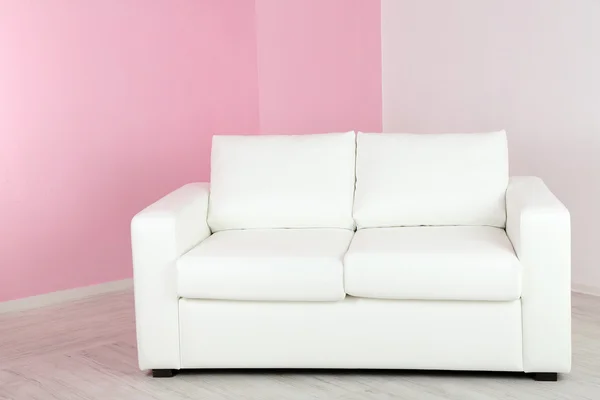 Vit soffa i rum på rosa vägg bakgrund — Stockfoto
