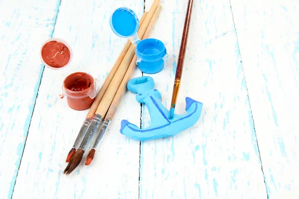 Hand made ceramic anchor and color paints on wooden table — Stock Photo, Image