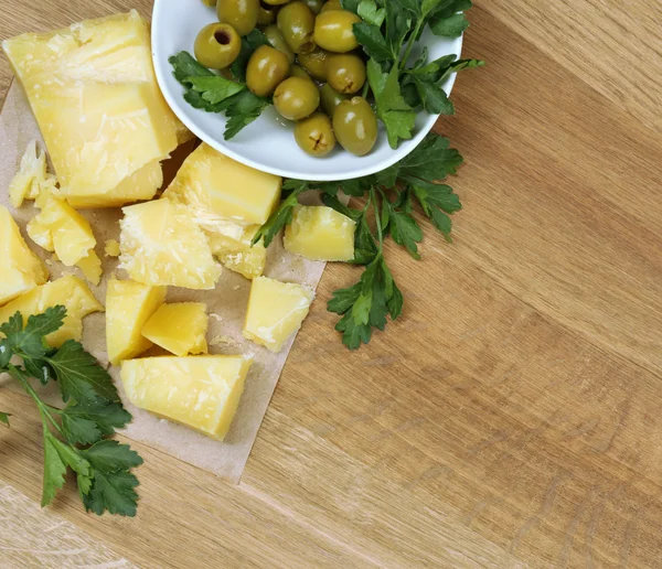 Parmesan cheese, fresh herbs and olives on wooden background — Stock Photo, Image