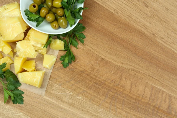 Parmezaanse kaas, verse kruiden en olijven op houten achtergrond — Stockfoto