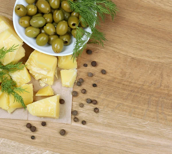 Sýr parmezán, čerstvé bylinky a olivy na dřevěné pozadí — Stock fotografie
