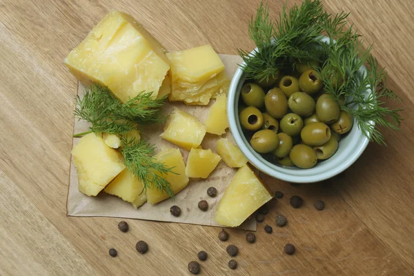 Sýr parmezán, čerstvé bylinky a olivy na dřevěné pozadí — Stock fotografie