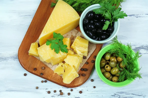 Parmesan cheese, fresh herbs and olives on wooden background — Stock Photo, Image
