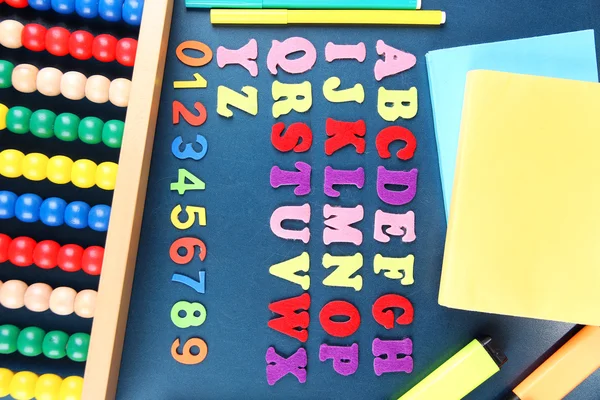Números coloridos, ábaco, libros y marcadores en el fondo del escritorio de la escuela — Foto de Stock