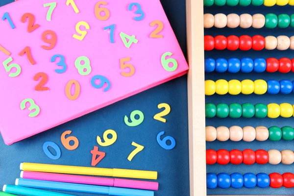 Numeri colorati, abaco, libri e pennarelli sullo sfondo della scrivania della scuola — Foto Stock