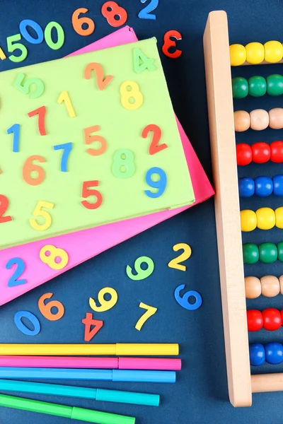 Numeri colorati, abaco, libri e pennarelli sullo sfondo della scrivania della scuola — Foto Stock