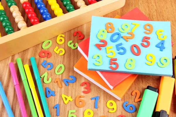 Kleurrijke nummers, abacus, boeken en markers op houten achtergrond — Stockfoto