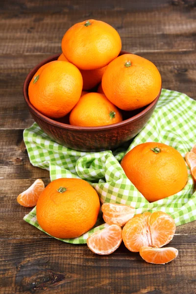 Спелые сладкие мандарины со специями в миске, на салфетке, на деревянном фоне — стоковое фото