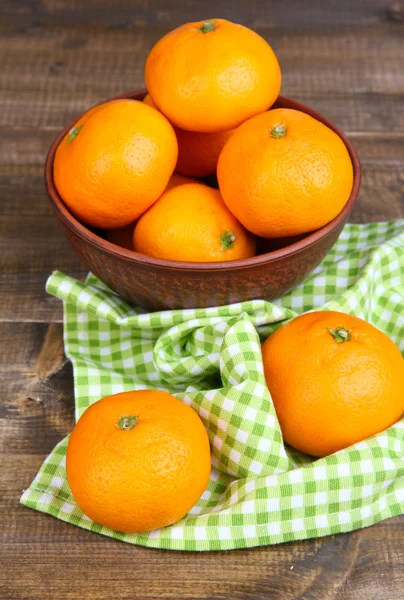 Ripe sweet tangerines with spices in bowl, on napkin, on wooden background — Stock Photo, Image