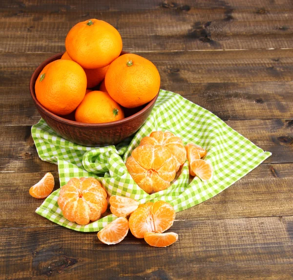 Ripe sweet tangerines with spices in bowl, on napkin, on wooden background — Stock Photo, Image