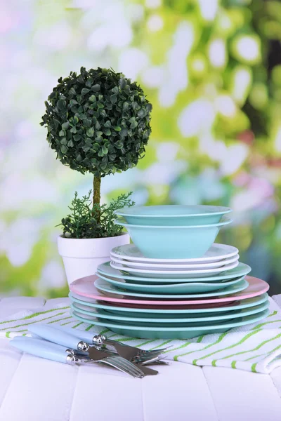 Sauberes Geschirr mit Blume auf Holztisch vor natürlichem Hintergrund — Stockfoto