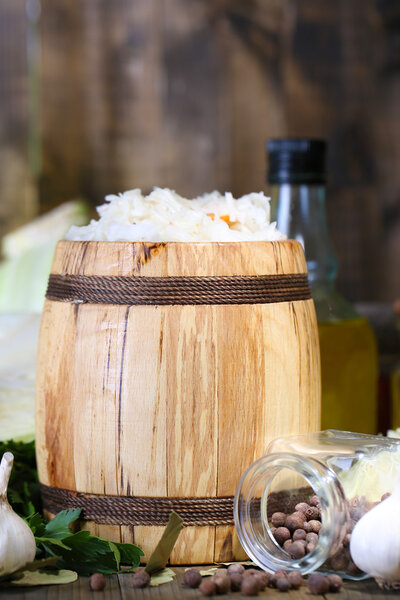 Composition with fresh and marinated cabbage (sauerkraut) in wooden barrel, on wooden table background
