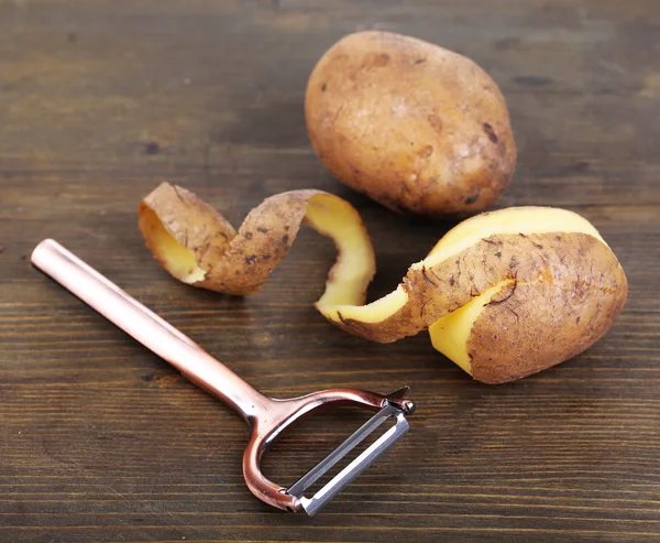 Skrobak i świeżego ziemniaka na drewniane tła — Zdjęcie stockowe