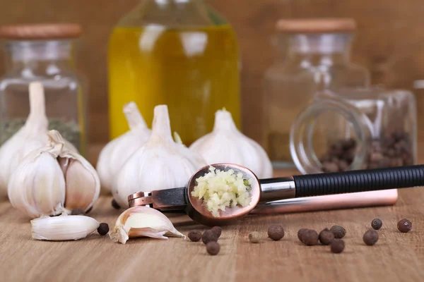 Composición con prensa de ajo, ajo fresco y frascos de vidrio con especias sobre fondo de madera — Foto de Stock