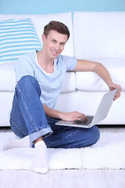 Killen sitter på golvet med laptop på rummet bakgrund — Stockfoto