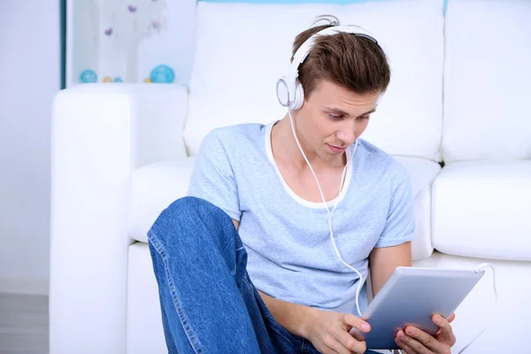 Guy sitting on floor and listening to music on room background — Stock Photo, Image