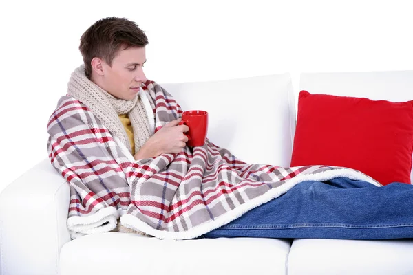 Guy wrapped in plaid lies on sofa on white background — Stock Photo, Image