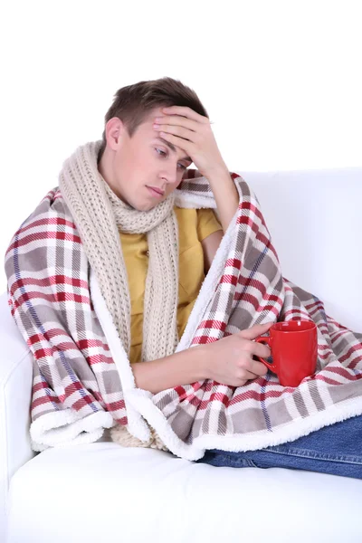 Guy wrapped in plaid lies on sofa on white background — Stock Photo, Image