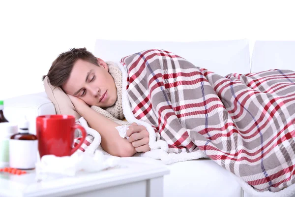 Kerel verpakt in geruite ligt op sofa is ziek — Stockfoto