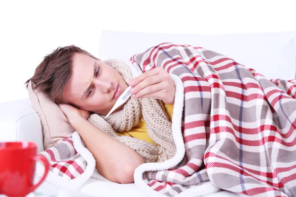 Guy wrapped in plaid lies on sofa is ill — Stock Photo, Image