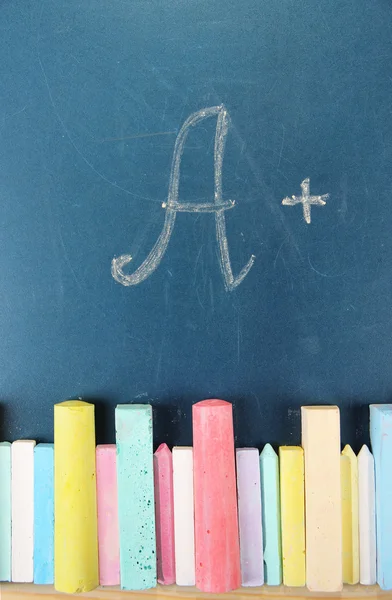 Оценка образования и разноцветные мелы на школьном столе — стоковое фото