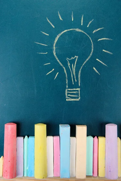 Colorful chalks and drawing on school desk — Stock Photo, Image