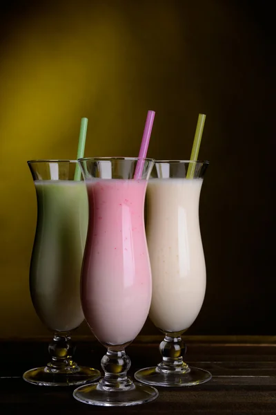 Milk shakes on table on dark yellow background — Stock Photo, Image