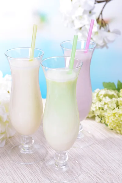 Milk shakes on table on light blue background — Stock Photo, Image