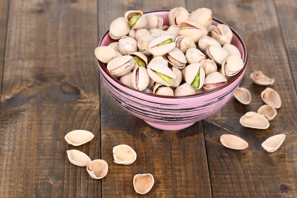 Pistacchi in ciotola su fondo di legno — Foto Stock