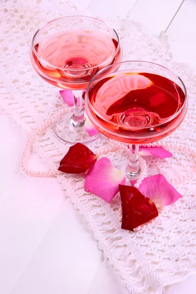 Kompozycja z różowy skrzyć wino w okularach i płatki róż na białym tle — Zdjęcie stockowe