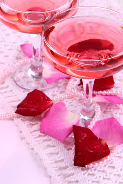Kompozycja z różowy skrzyć wino w okularach i płatki róż na białym tle — Zdjęcie stockowe