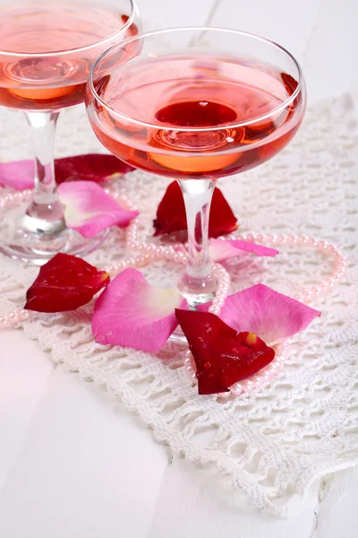 Sammansättning med rosa gnistra vin i glasen och rosenblad isolerad på vit — Stockfoto