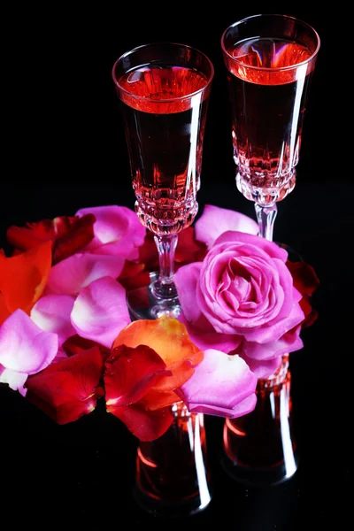 Composizione con vino rosa in calici, bottiglia e rose isolate su fondo nero — Foto Stock